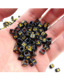 Letra dorada. Cubo negro. 6 milímetros lado. 3 mm perforación. 100 unidades aproximado.